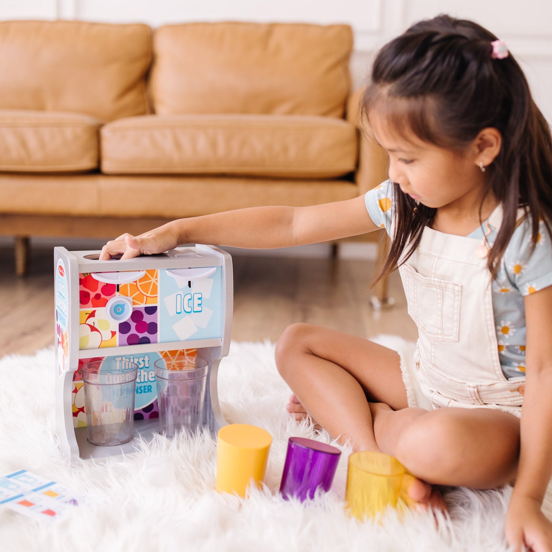 A kid playing with The Melissa & Doug Wooden Thirst Quencher Drink Dispenser With Cups, Juice Inserts, Ice Cubes