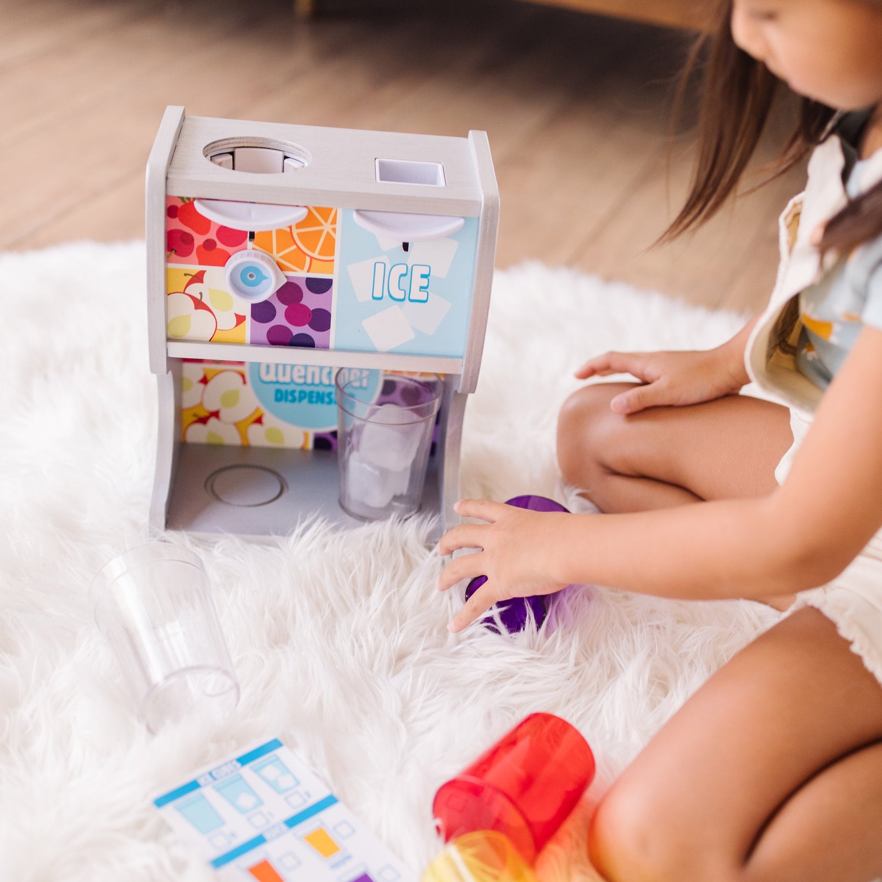 A kid playing with The Melissa & Doug Wooden Thirst Quencher Drink Dispenser With Cups, Juice Inserts, Ice Cubes